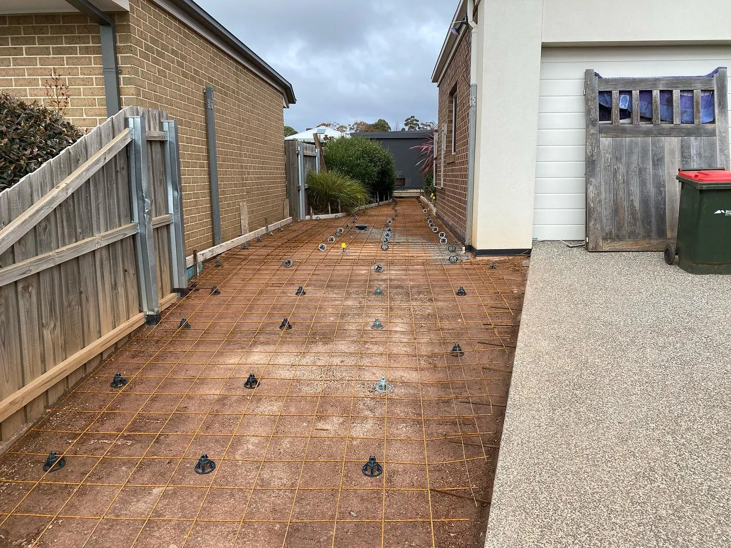 Side-of-house mesh and chairs laid on sand for the aggregate path pour
