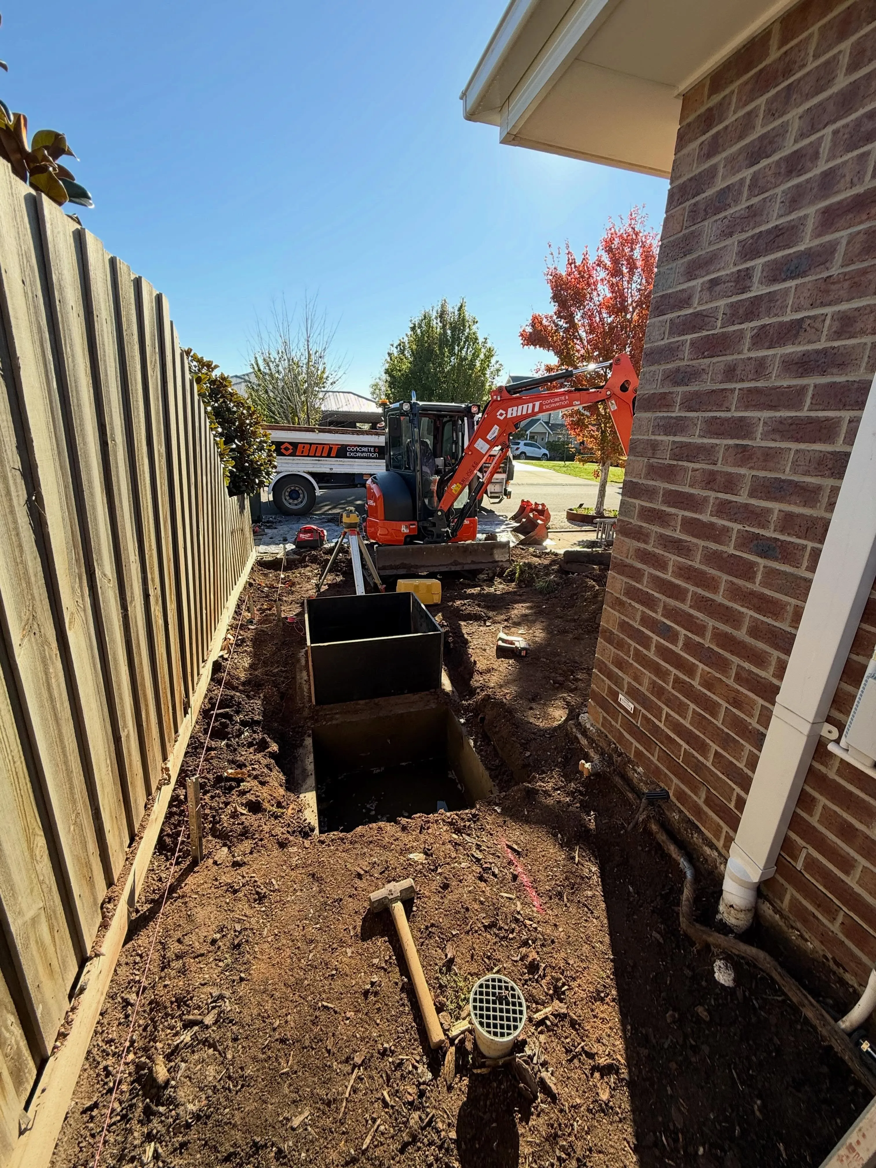 Trench cut beside the brick house with a BMT mini-excavator working