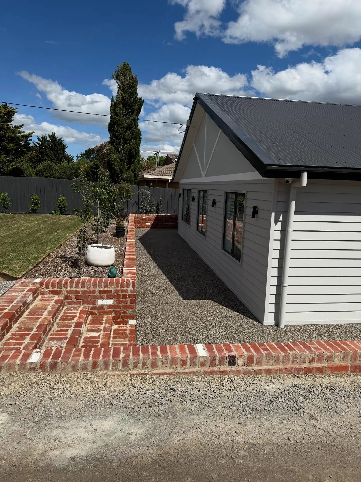 Charcoal concrete apron and matching steps at a grey-and-white weatherboard cottage