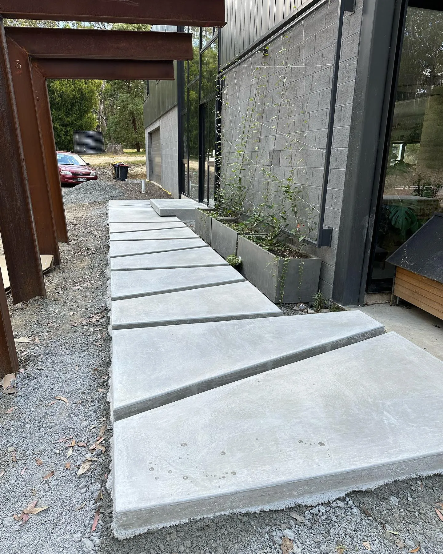Wide view of staggered offset concrete pavers running along the glass and timber facade