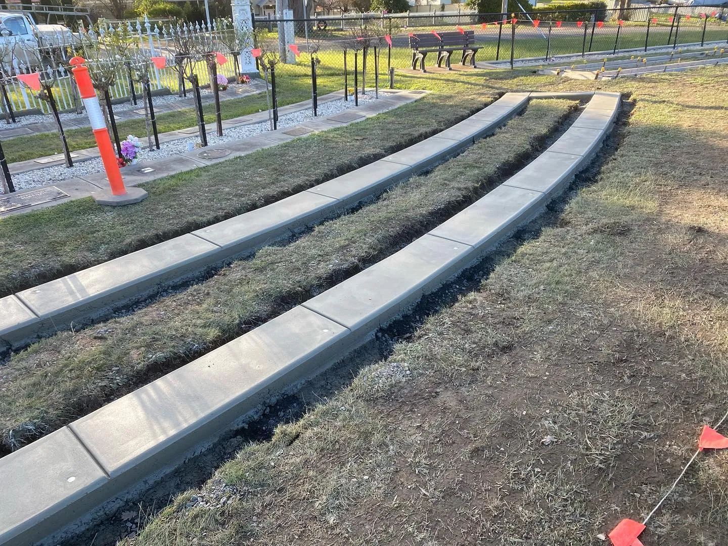 Finished curved concrete kerb edges across multiple rows of a memorial garden