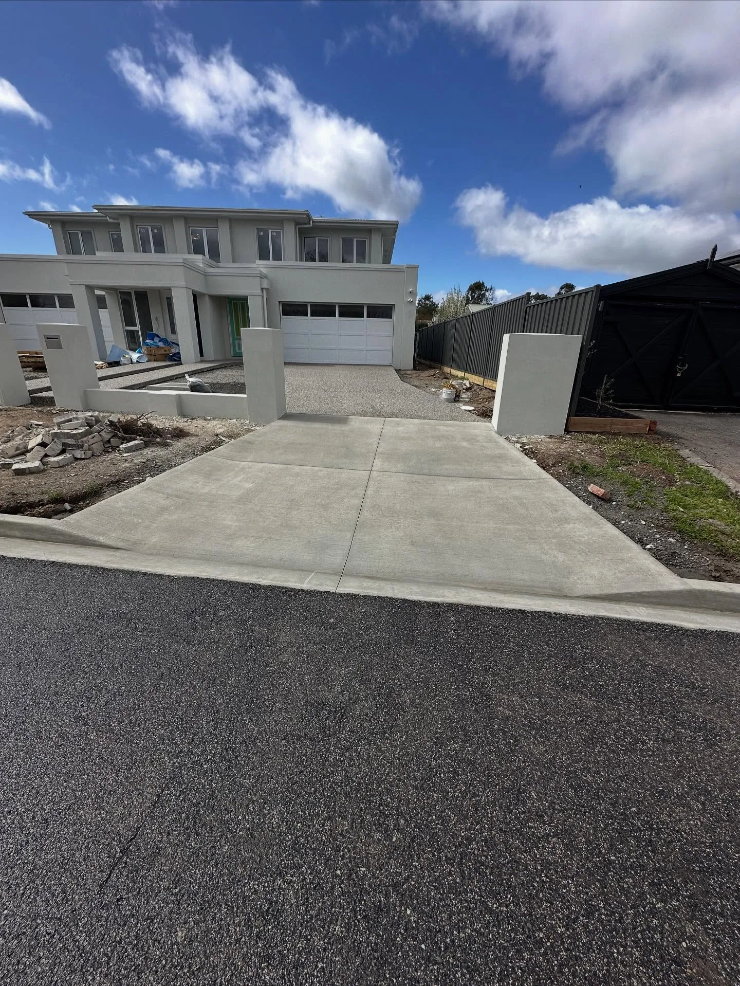 Council-spec concrete cross-over running from the kerb up to the double-garage entry of a new build, neatly finished to the road edge