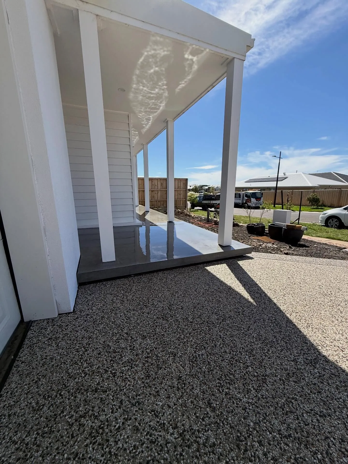 Charcoal porch slab transitioning to an exposed aggregate driveway at a new build