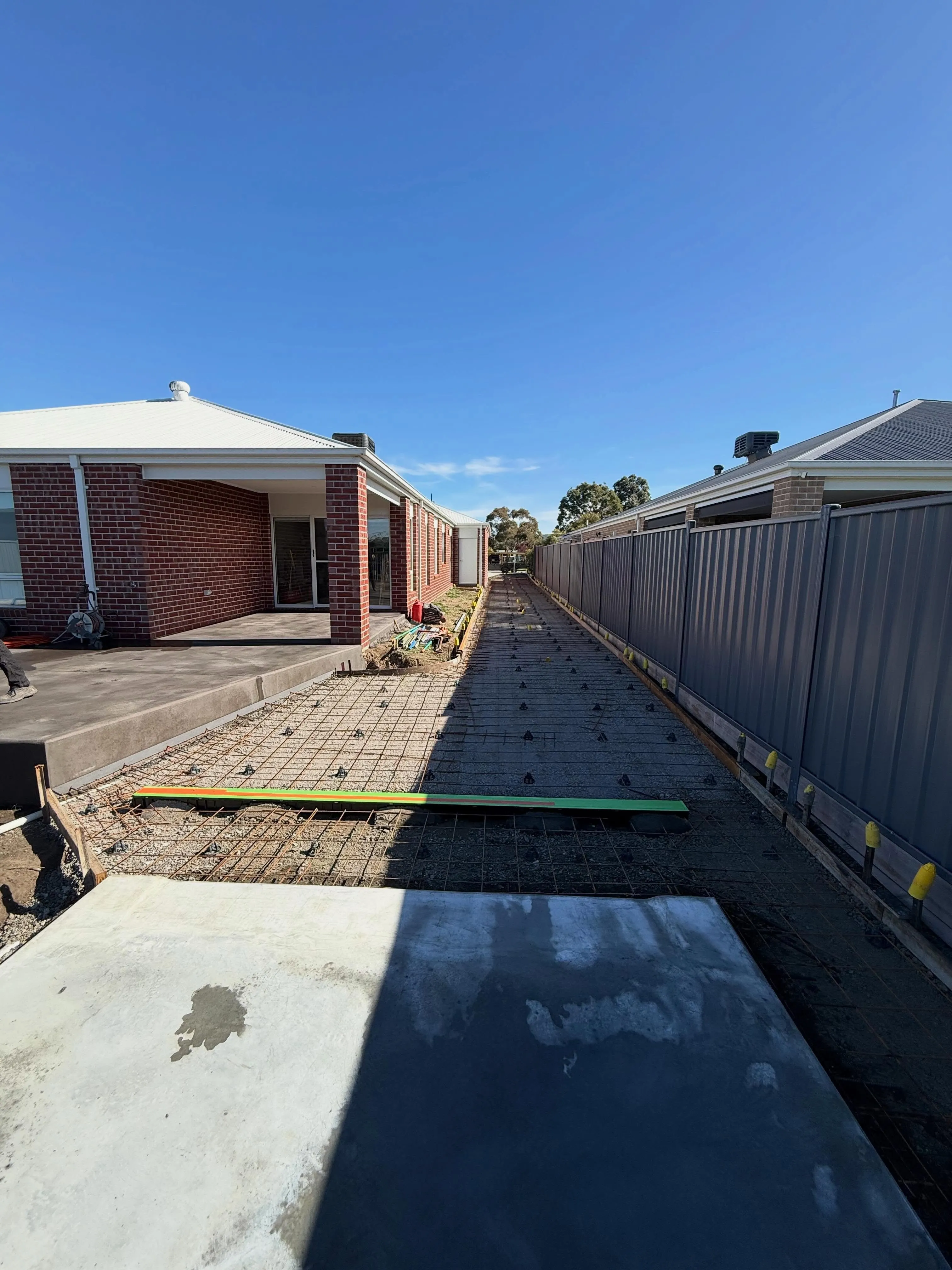 Long mesh and timber screed strip running between two brick homes pre-pour