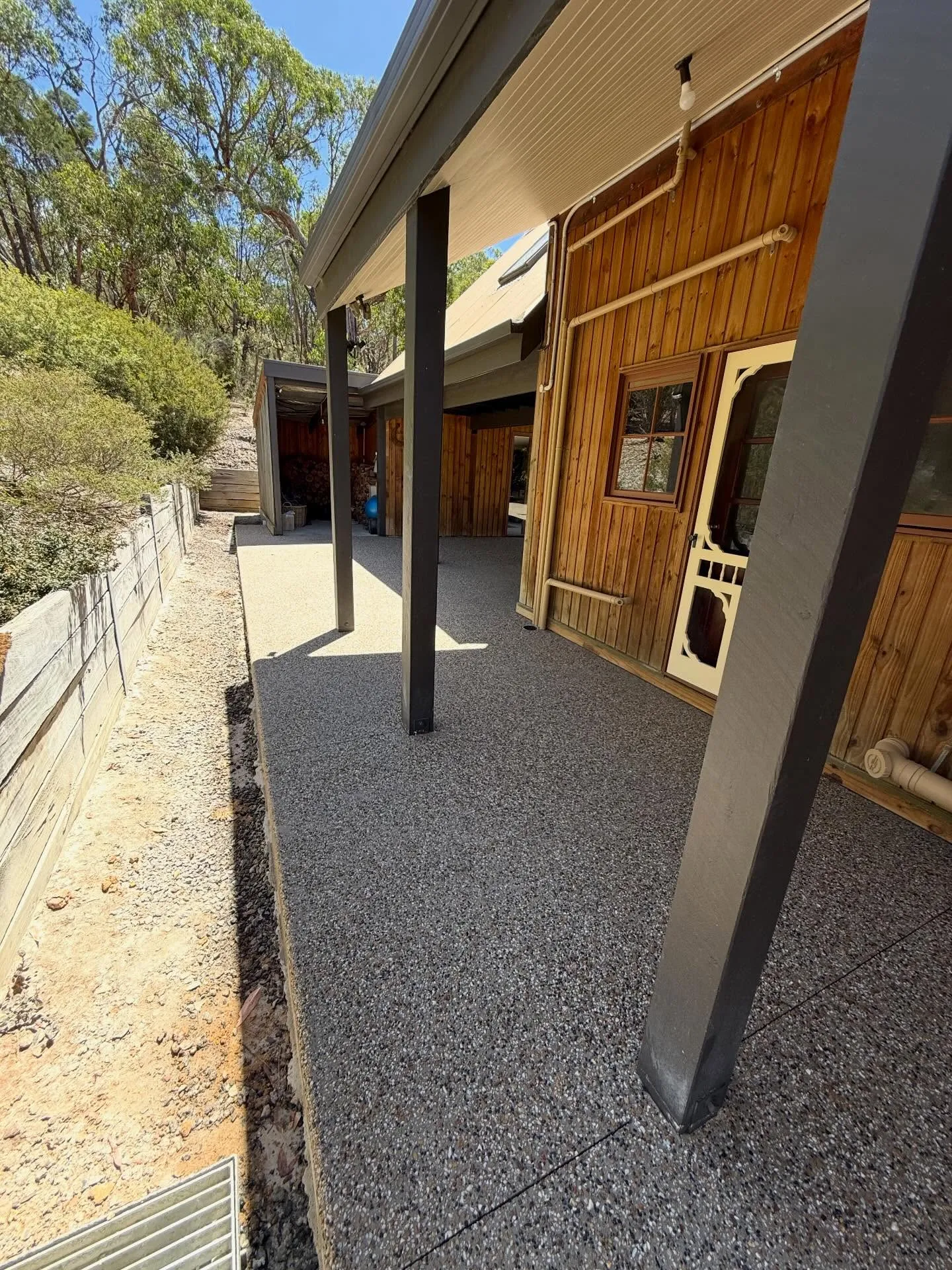 Exposed aggregate verandah on a mud-brick and timber bush home, soft afternoon light