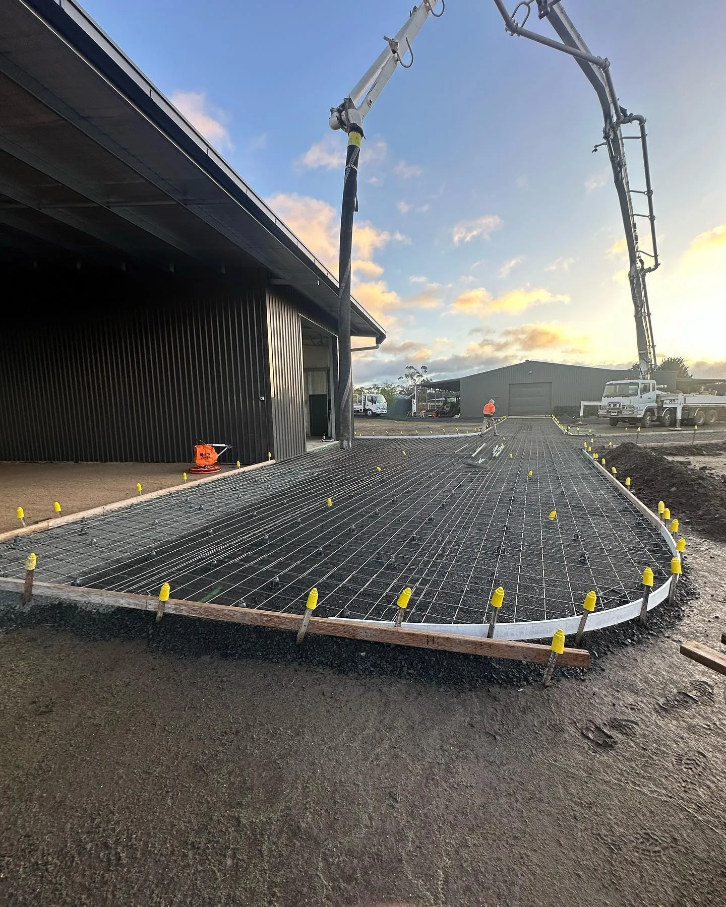 Concrete pump truck delivering on a large shed slab at golden hour