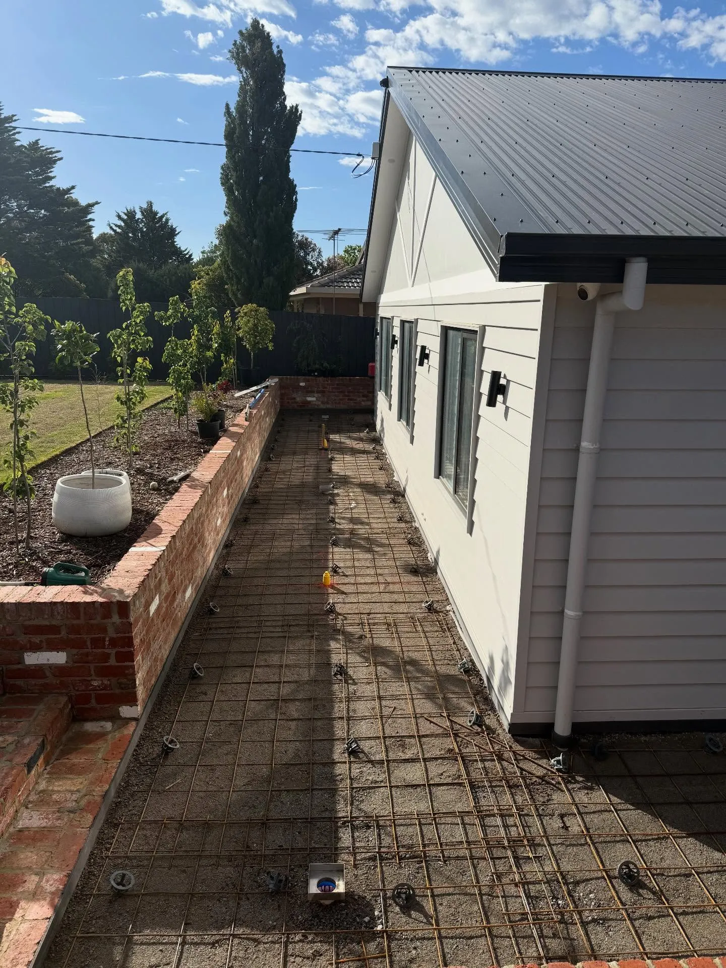 Tight plain concrete side path between a weatherboard home and a timber fence