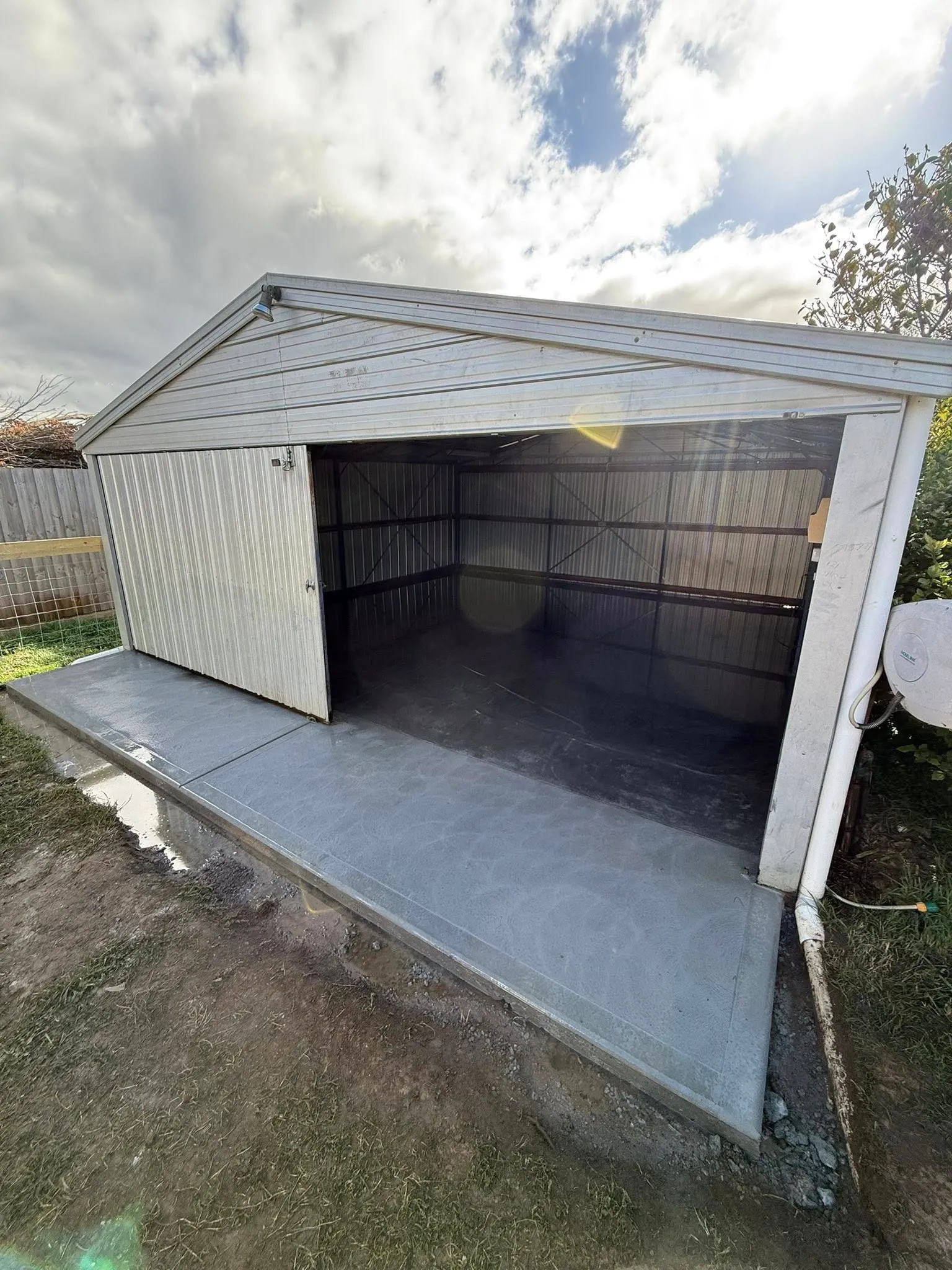 Newly poured concrete floor and apron for a small garden shed by the kerb