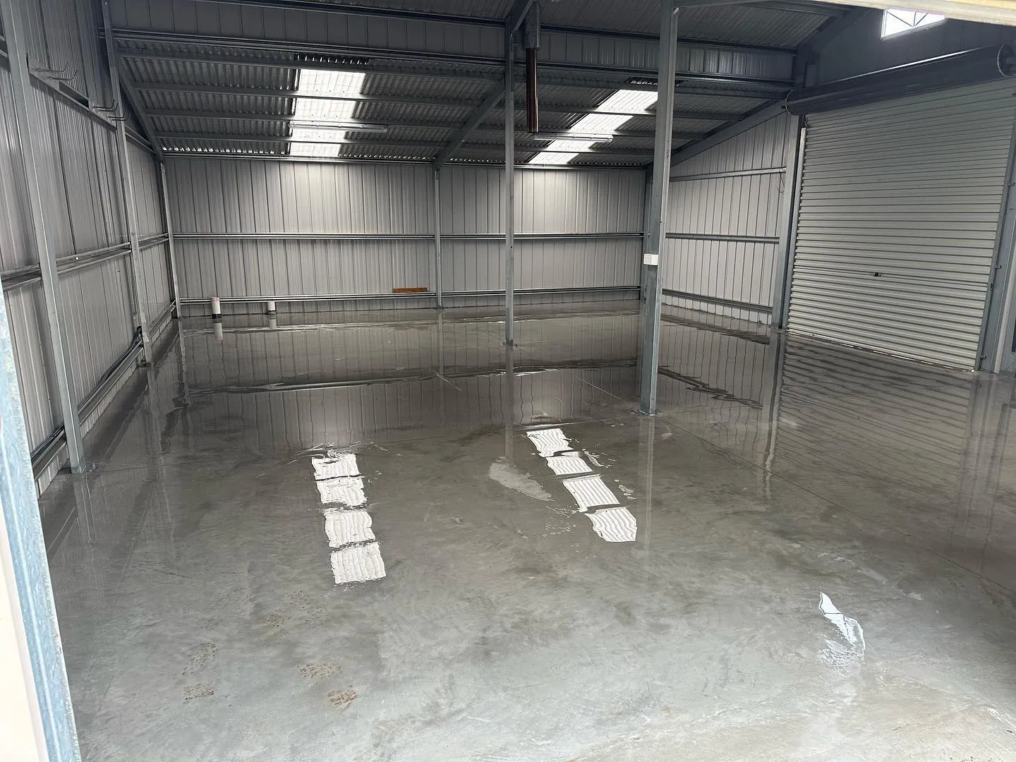 Finished rural shed slab on a hilltop next to a galvanised water tank