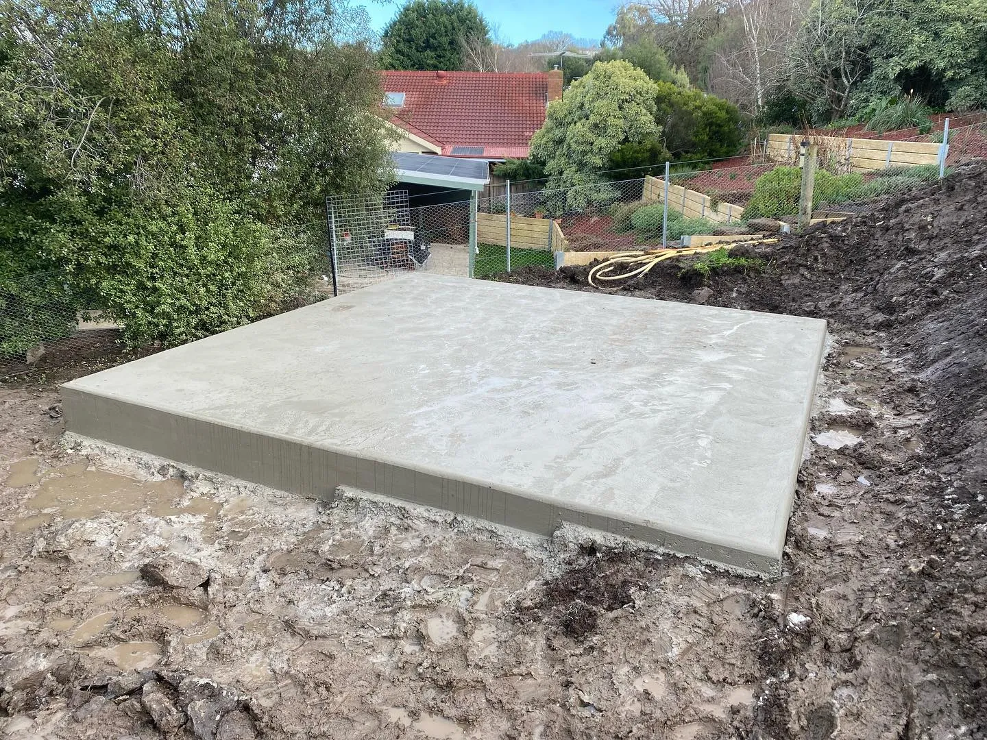 Big clean square shed slab sitting in cut earth on a sloping rural block