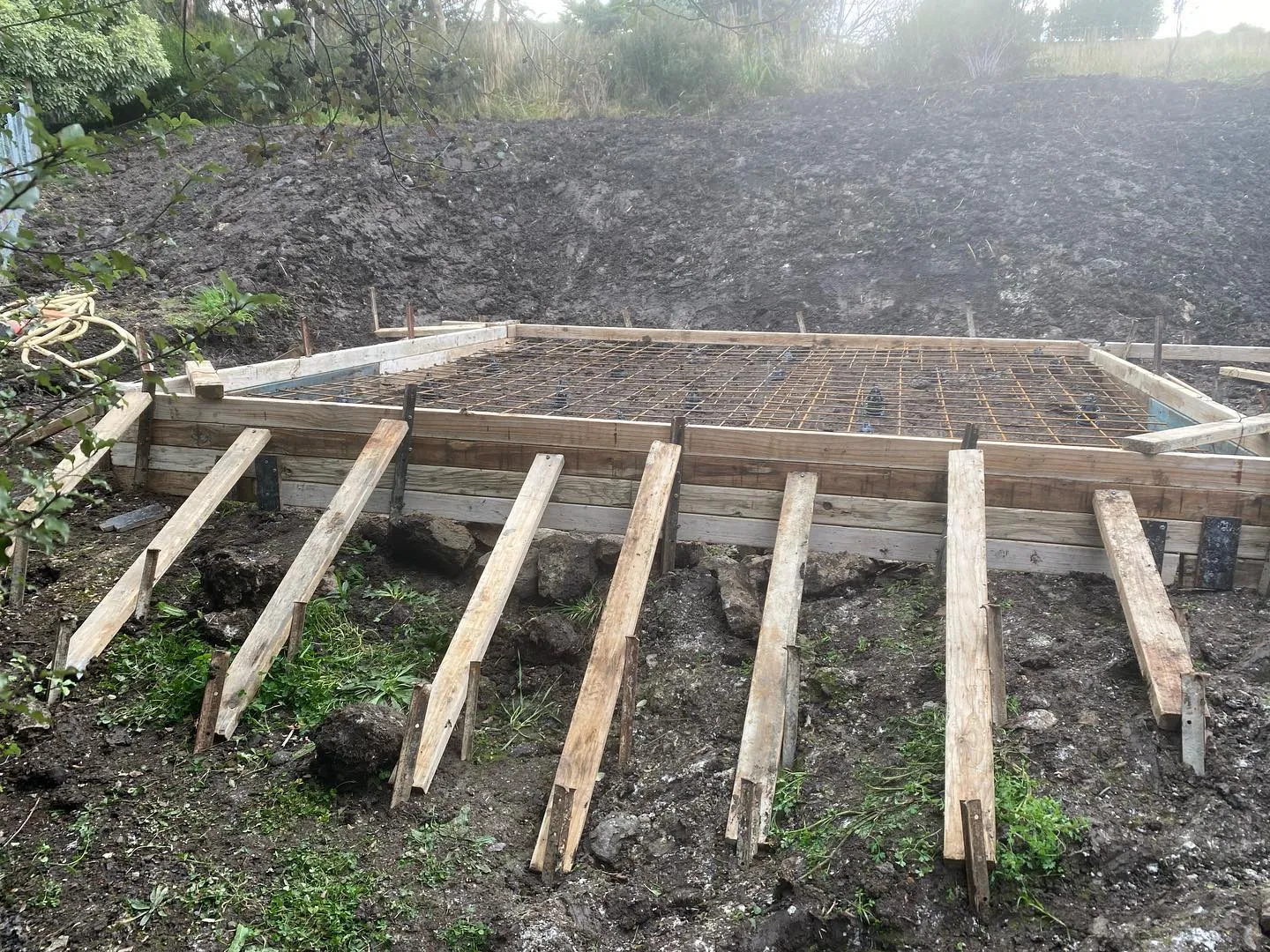 Square slab formwork with timber braces cut into the sloping rural block